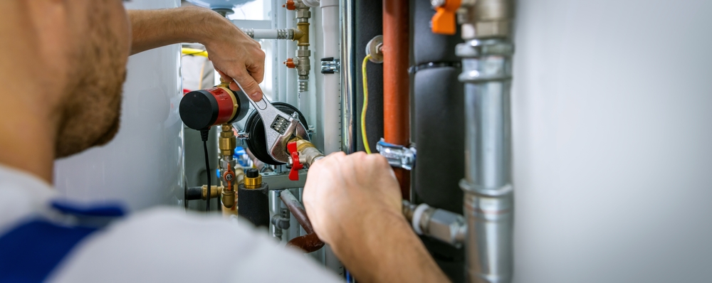 Plumbing technician tightening a brass fitting on copper supply lines with a wrench